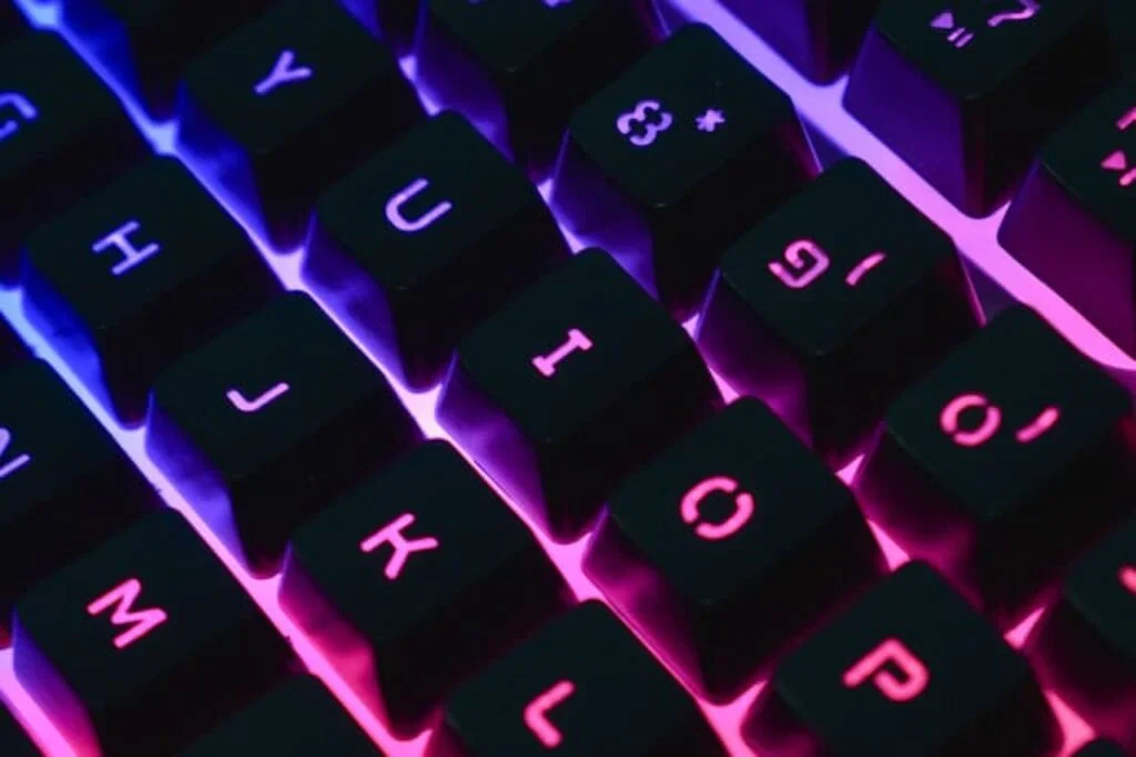 close up de um teclado mecânico com iluminação rosa e azul