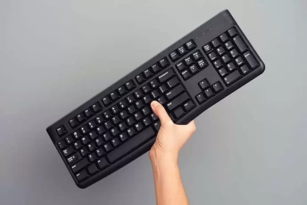 pessoa segurando um teclado com apenas uma mão