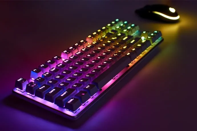 Um teclado e um mouse gamer com led em cima de uma mesa.