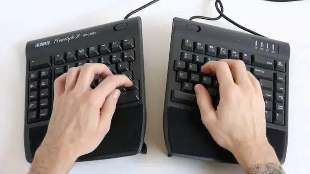 Pessoa mexendo em um teclado ergonômico separado em duas partes. 