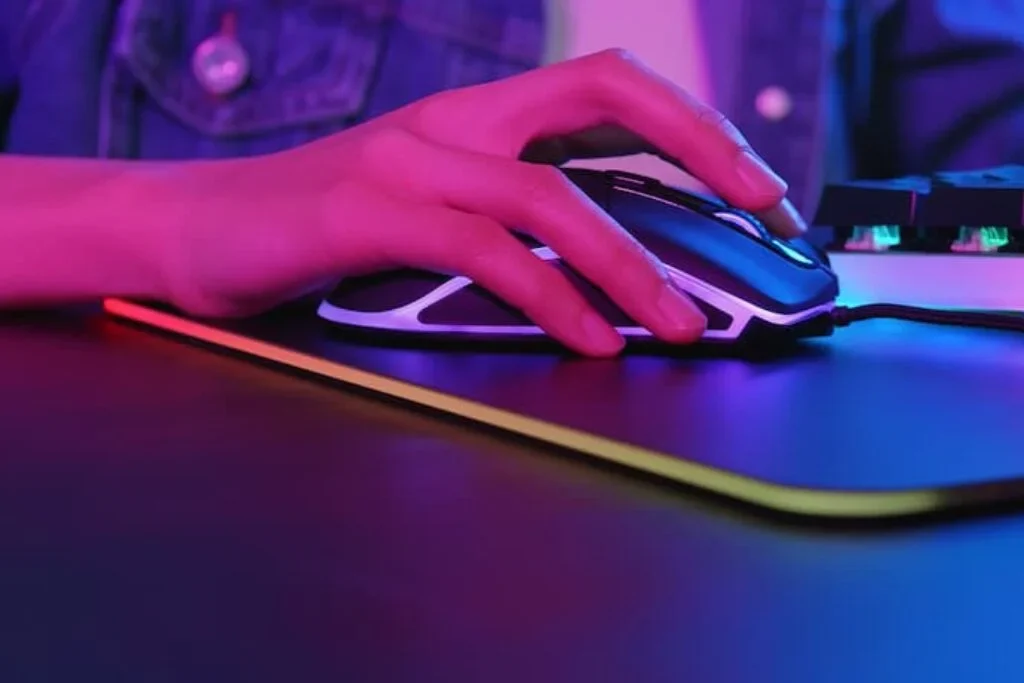 UMA MÃO CLICANDO EM UM MOUSE GAMER.