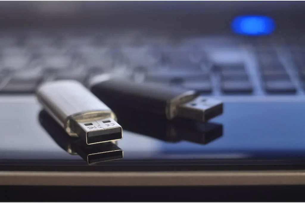 Dois modelos diferentes de pen drive em cima de um teclado de notebook.