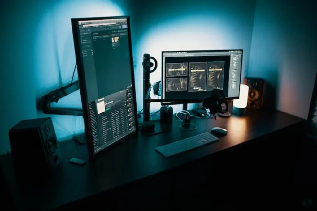 Um computador gamer com duas telas e ao fundo uma luz de led branca.
