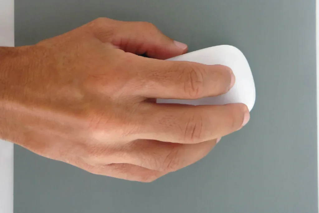 Uma pessoa clicando em um mouse sem fio de cor branca.