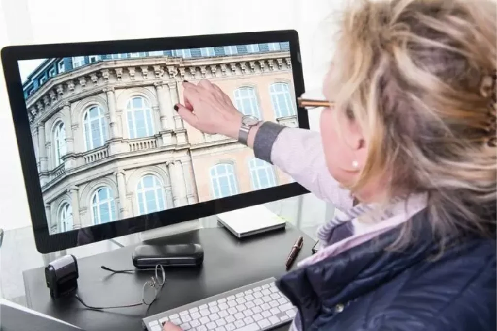 Uma mulher mostrando uma imagem de um centro histórico pelo computador.
