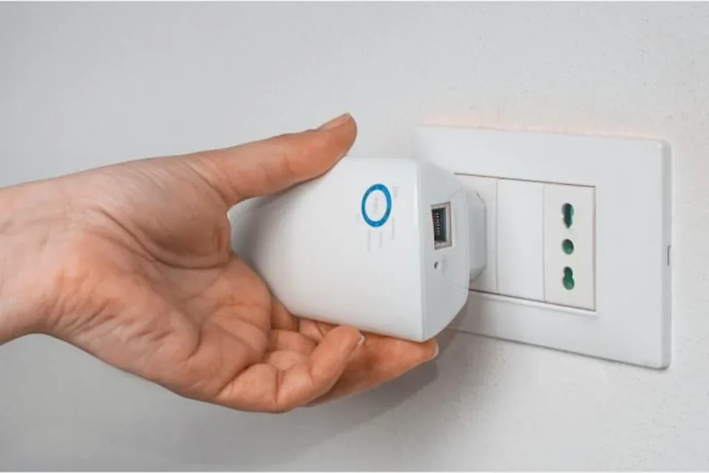 Uma pessoa conectando um repetidor de sinal de Wi-fi para melhorar sua internet.