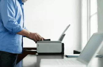 Homem usando impressora branca em escritório.