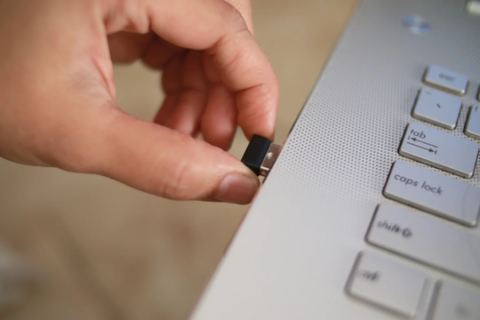 Pessoa inserindo adaptador bluetooth em notebook.